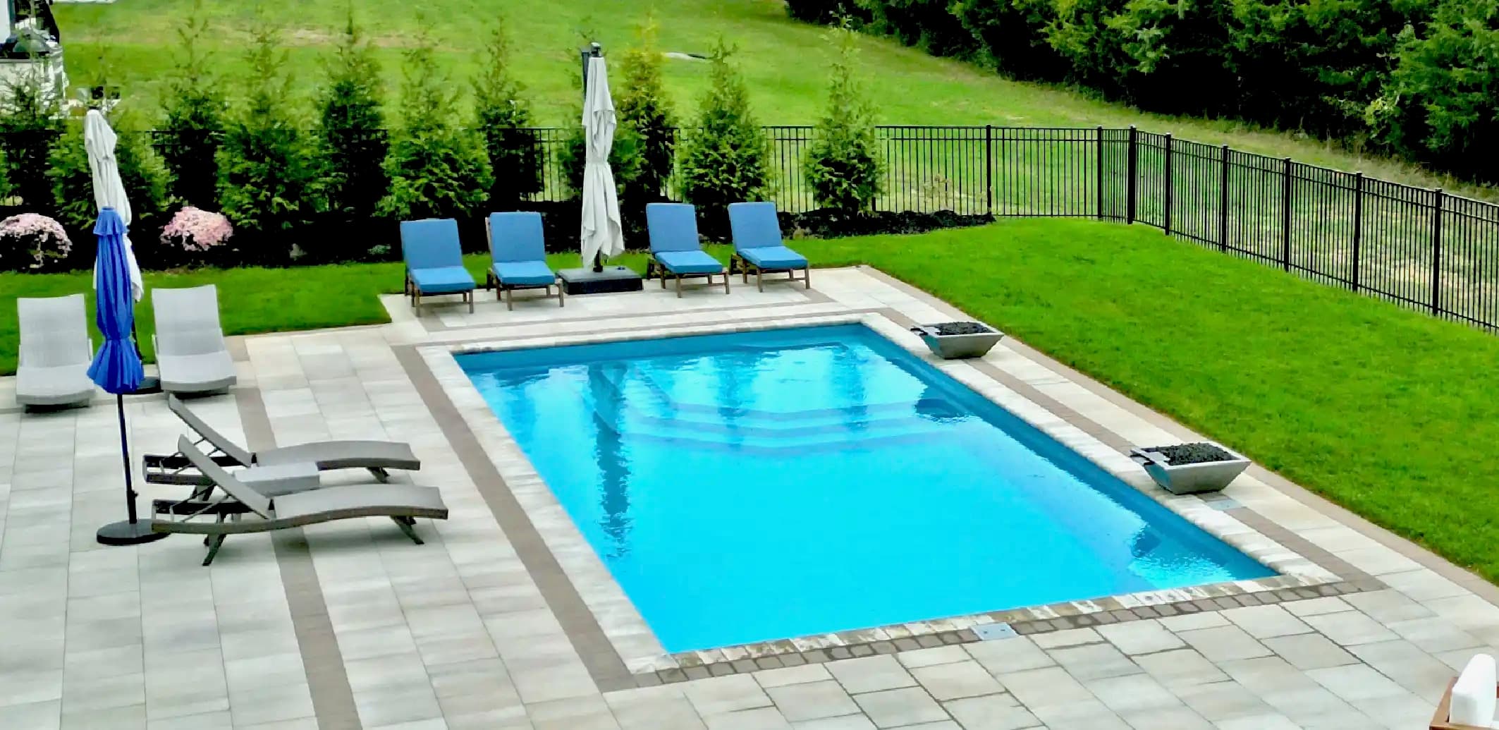 Aviva fiberglass rectangular in-ground pool with paver decking and chaise lounges